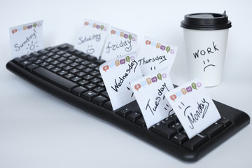 on the black keyboard many stickers with the names of the days of the week. next to a paper Cup of...