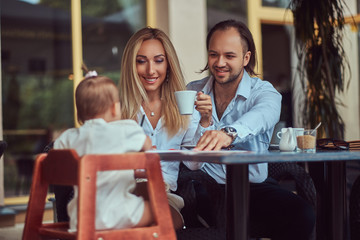 Family and people concept - happy mother, father and the little girl in outdoor cafe.
