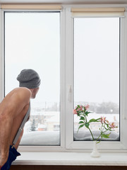 Man looking in window on cold winter day at home