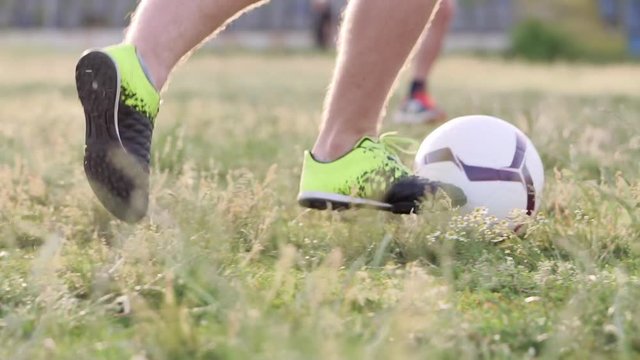 Slide slow motion a football stunts. The football player throws the ball alternately with his feet. A teenager is playing on an abandoned football field at sunset 