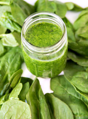 Green smoothie in jar, overhead on glass, healthy drink with vegetable leaves, background