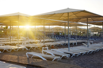 Sun loungers with umbrella on the beach. Tourism industry.