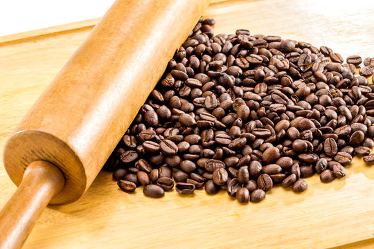 Roasted Brown coffee beans and Wooden rolling pin on wood background Close Up .new Grinding coffee strange