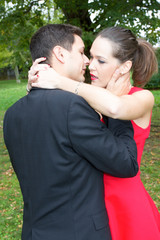 Elegant woman wearing a red dress leaning on her lover embracing man love concept