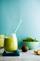 Healthy green smoothie with baby kale, passion fruits, ginger and chia seeds  and avocado  in glass with blue  straw against a gray background. Detox, diet, healthy,