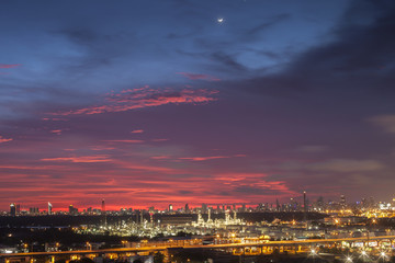 A night landscape view of city and Oil refinery industry under colorful sky at sunset time