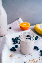 Smoothies for the summer detox made with banana, blueberries, oranges and oat classic, over a white towel against a gray background