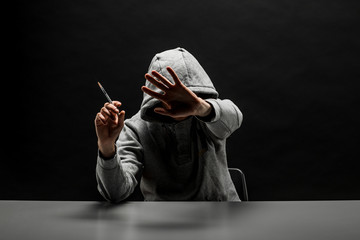 Addict in gray hoodie on the head suffers from addiction on a dark black background