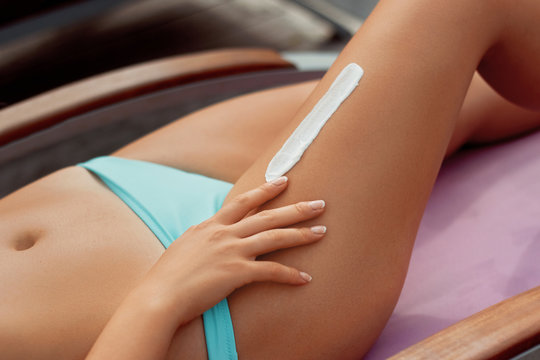 Beautiful Legs  with Sunscreen. Skin Care. Woman Applying Sun Cream On Skin on Legs. Sun cream on Feet. Epilation Laser or Shaving Concept.