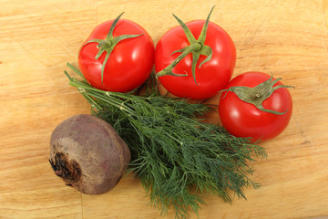 Beetroot, three ripe tomatoes and bunch of the fresh dill leaves on a cutting board