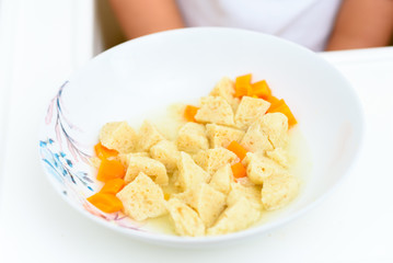 Top view of soup in plate for Child.Traditional matzoh ball (kneidlach) soup.White  bowl with authentic matzo ball chicken taste hot soup ( bouillon ) tradition Jewish food for Passover and every day.