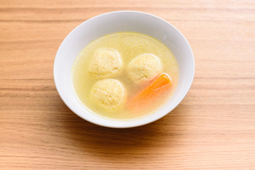 Traditional matzoh ball (kneidlach) soup.White  bowl with authentic matzo ball chicken taste hot soup ( bouillon ) tradition Jewish food for Passover and every day.