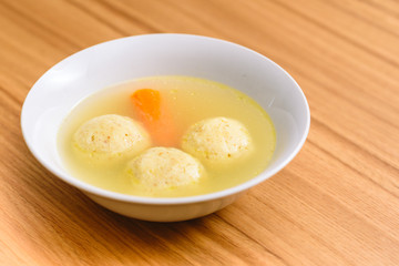 Traditional matzoh ball (kneidlach) soup.White  bowl with authentic matzo ball chicken taste hot soup ( bouillon ) tradition Jewish food for Passover and every day.