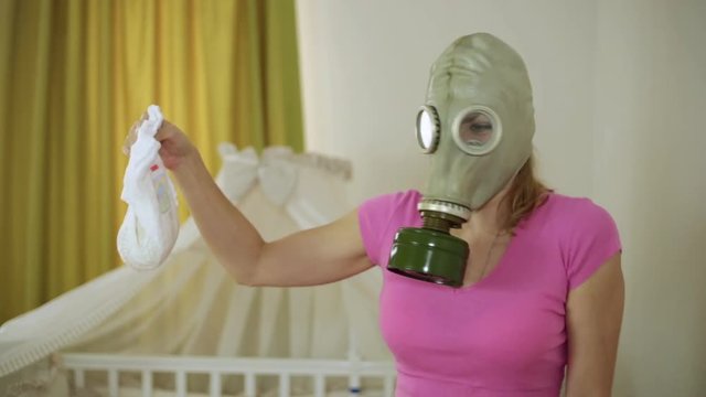 A woman in a gas mask looks disgustedly at the children's diaper