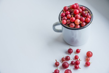 Summer berries in a white cup with red gooseberry on a white background.gooseberry red, fresh ripe berries, healthy food concept. detox life. Copy space