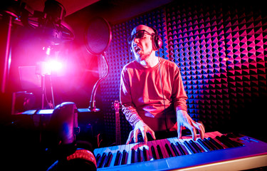 Young man playing piano in sound recording studio.