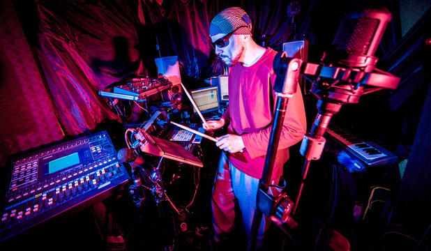 Young man playing on electric drum in sound recording studio.