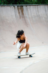 An attractive and young Chinese Asian girl is enjoying as she plays on a skating bowl. She is a very cool and fashionable skater girl.
