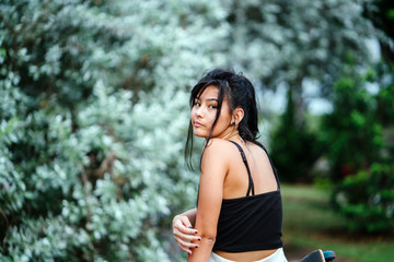 A portrait of an attractive and young Chinese skater girl sitting with her skateboard while waiting for her friends at the skate park.