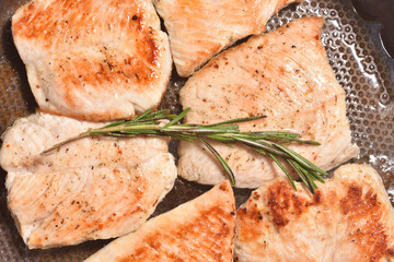 A branch of fragrant and fresh rosemary on roasted turkey meat in a frying pan. Close-up