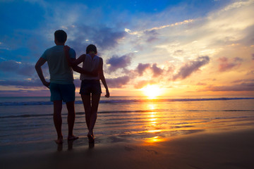 sunset silhouette of young couple in love hugging at beach