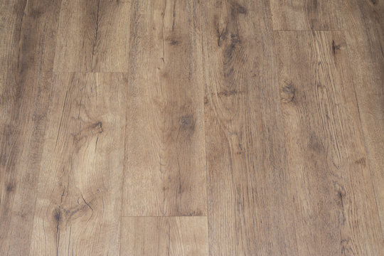 Modern vinyl floor with old wood imitation. Close-up of new beige flooring with texture from tiles with brown grains and knots. Decorative background of wooden boards.