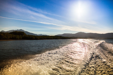 Speed boat driving along waving water reflect above of sun