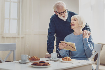 Family relations. Delighted nice man standing near his wife while hugging her