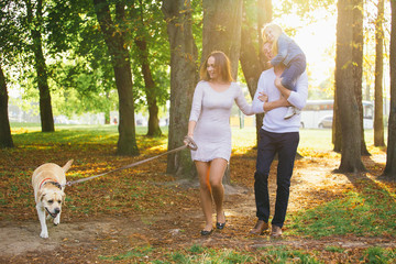 Obraz premium Happy family with their dog in the park on a sunny day