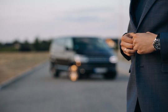 Man in suit stay in front of luxury car minivan