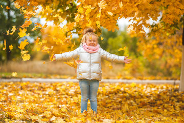 Cute child playing with autumn leaves