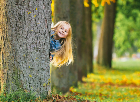 Little girl hugging a tree and smile in park