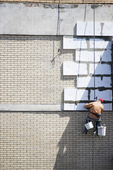 The worker insulates  facade of the apartment building.