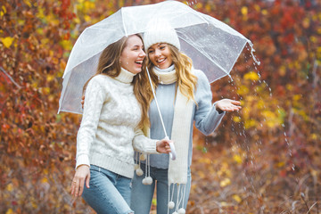 Young pretty girls having fun outdoors in autumn background. Cheerful friends in the fall time