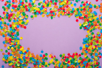 Frame made of colored confetti. Lilac and violet background.