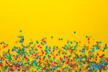 Colorful Confetti in front of orange Background.