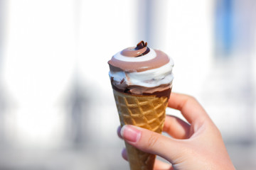 Ice cream cone, chocolate ice cream on blurred background, milk dessert on summer vacation, blank for designer with hand, copy space, milk product