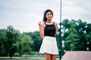 A  very cool and young Chinese Asian teenager standing stunningly as she poses into the camera during the day.