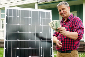 Solar panel. Money in the hands of men . Energy production technologies. Wooden house background. Saving.