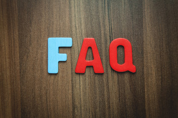 Colorful wooden word FAQ on a wood background.