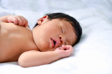 Newborn Concept. Newborn babies are sleeping in a bed. The baby is in the white bedroom.