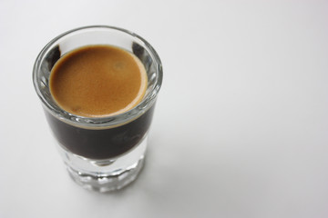 Espresso shot glass full of coffee with crema from above 