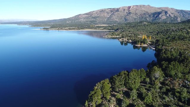 Aerial drone scene of Alumine lake. Camera travels fowards with a high point of view of bays, beaches, rocky and coasts. Mountains on the background. Touristic area five lagoons. Mapuche area.