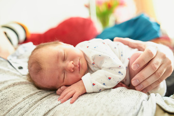 Newborn baby girl sleeping on her father's chest