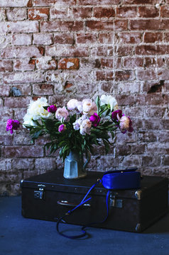 Colorful peony and vintage suitcase in loft interior space