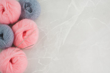 Pink and grey fluffy yarn balls on the left side of a marble background.