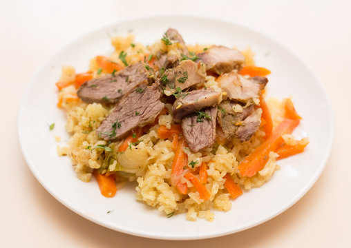 Rice with meat and vegetables on a white plate