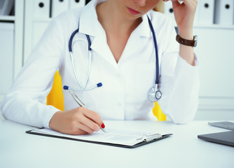 Close-up view of female doctor hands filling patient registration form. Healthcare and medical concept