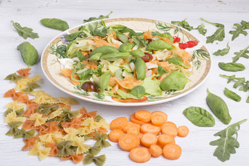 Pasta salad on a plate, with ingredients scattered on the table.