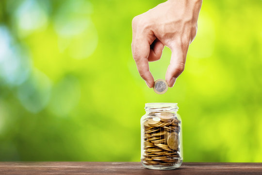 hand put money coins to glass jar